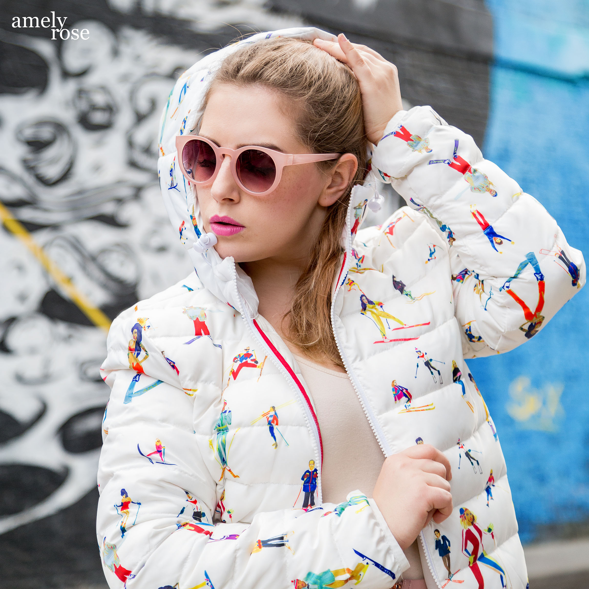 Amely Rose wearing a Designer Jacket infront of a blue Graffiti in London.